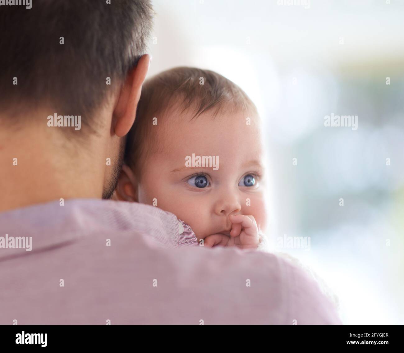 Daddys little angel. a baby girl looking over her fathers shoulder. Stock Photo