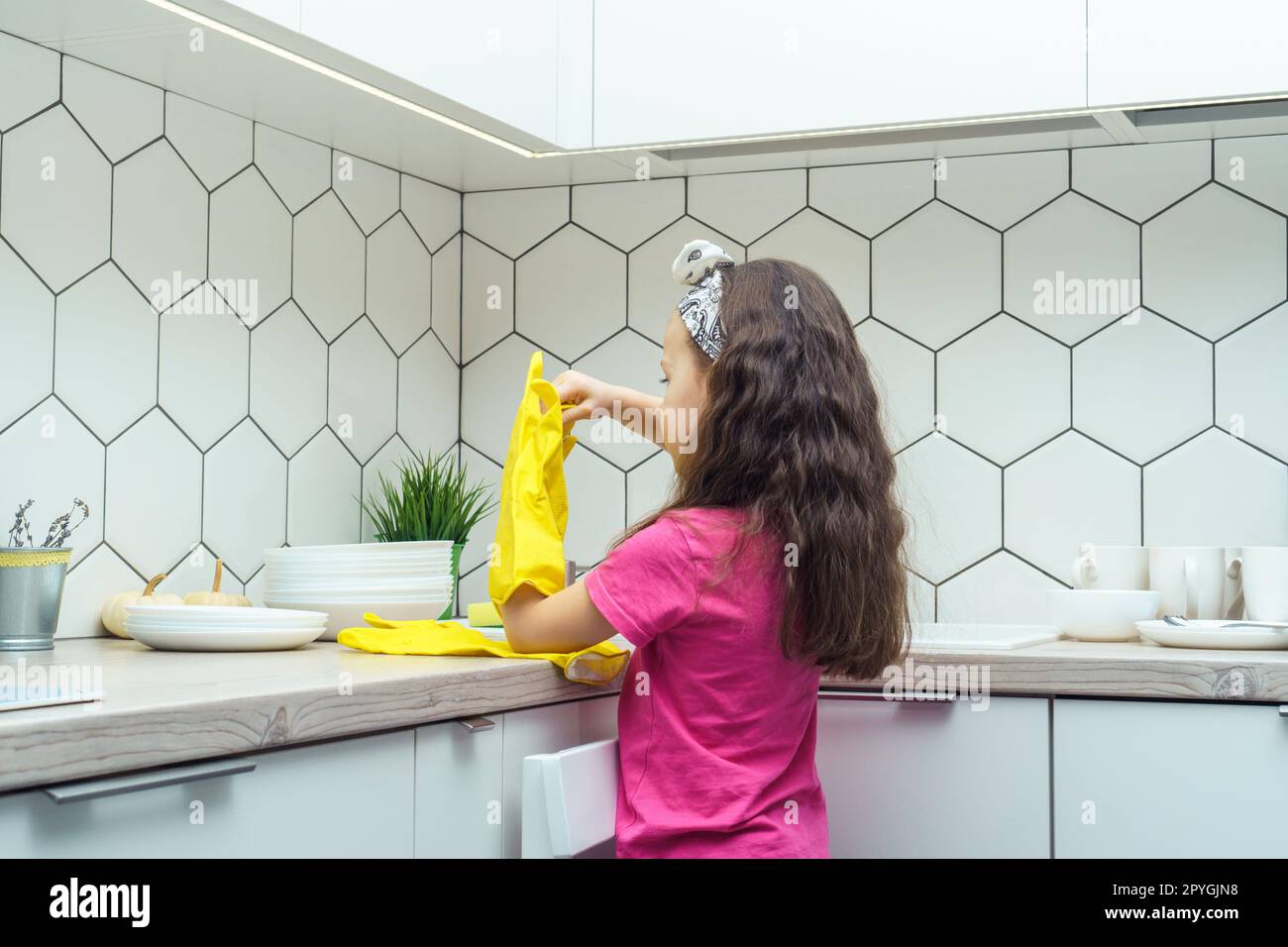 https://c8.alamy.com/comp/2PYGJN8/little-girl-taking-off-yellow-household-gloves-after-washing-up-dish-child-washing-tableware-in-kitchen-sink-back-view-2PYGJN8.jpg