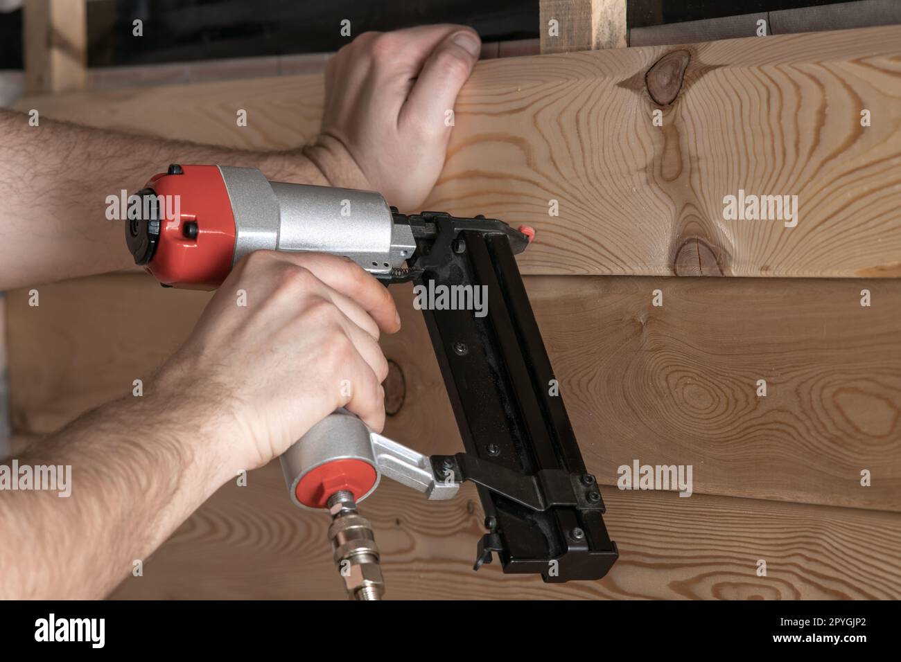 Unrecognizable cropped man hands using pneumatic stapler, nail gun for