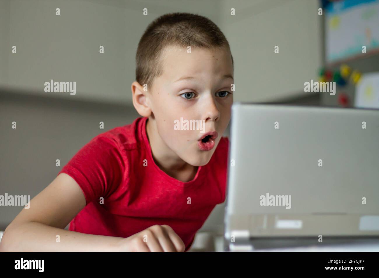 Boy 6-10 completes school lessons and homework online in the kitchen, looking at the tablet computer. Distant education. Stock Photo