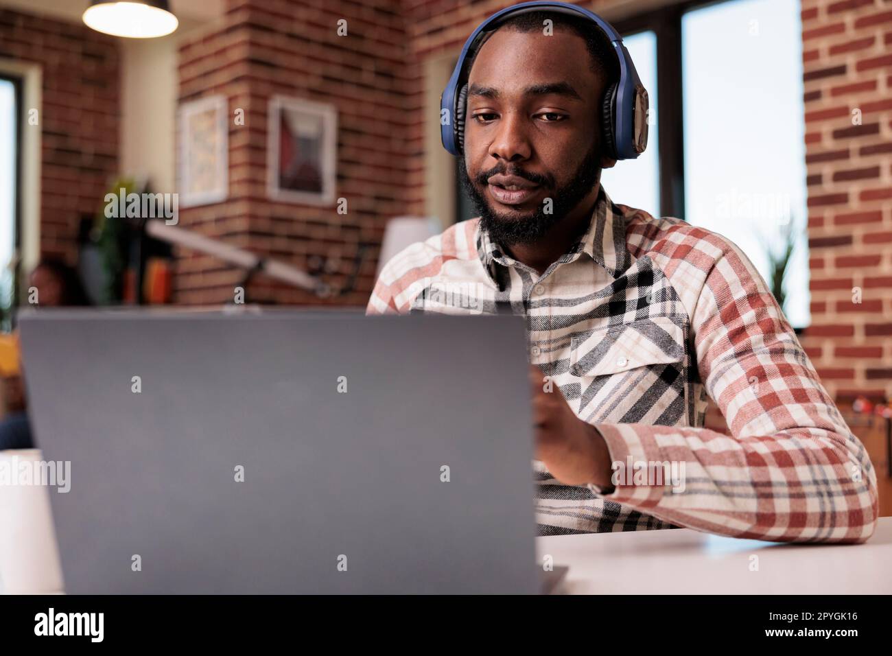 Freelancer with wireless headphones in video conference on laptop ...