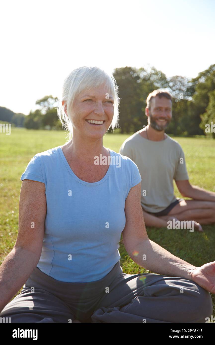 Dont take things too seriously. a happy mature couple doing yoga together outdoors. Stock Photo