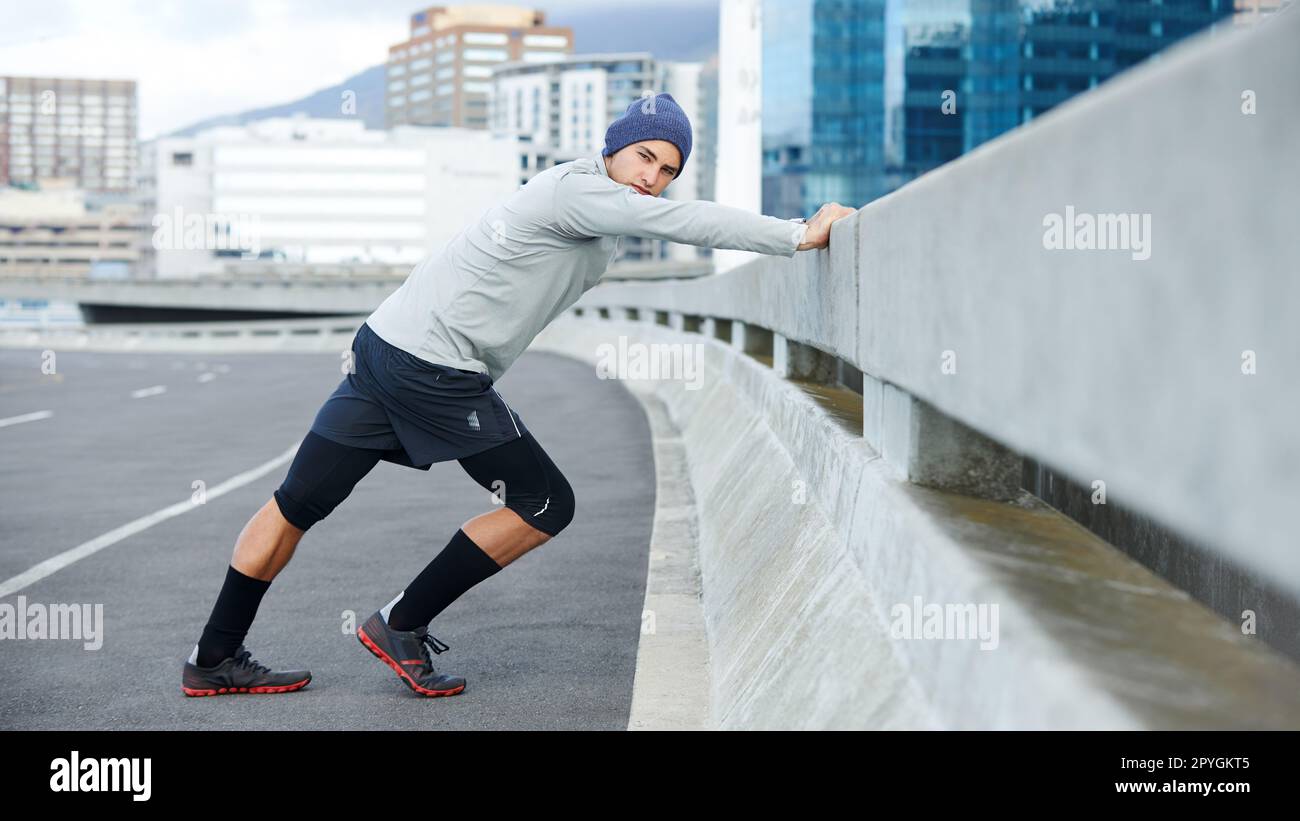 About to hit the pavement alone. a young man warming up for a jog