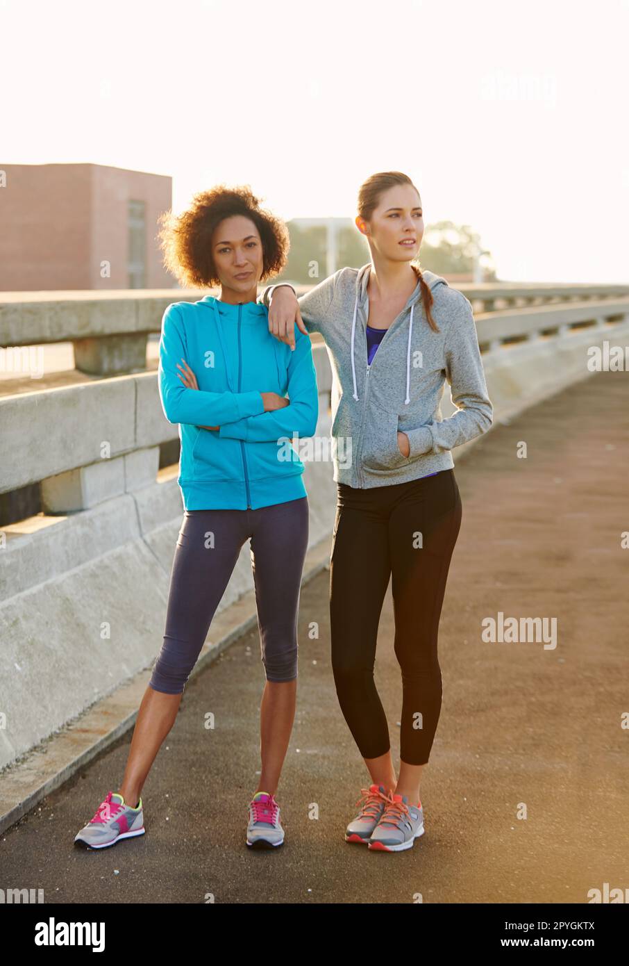 Prepared to go the distance. Portrait of two female joggers standing in the road before a run through the city. Stock Photo