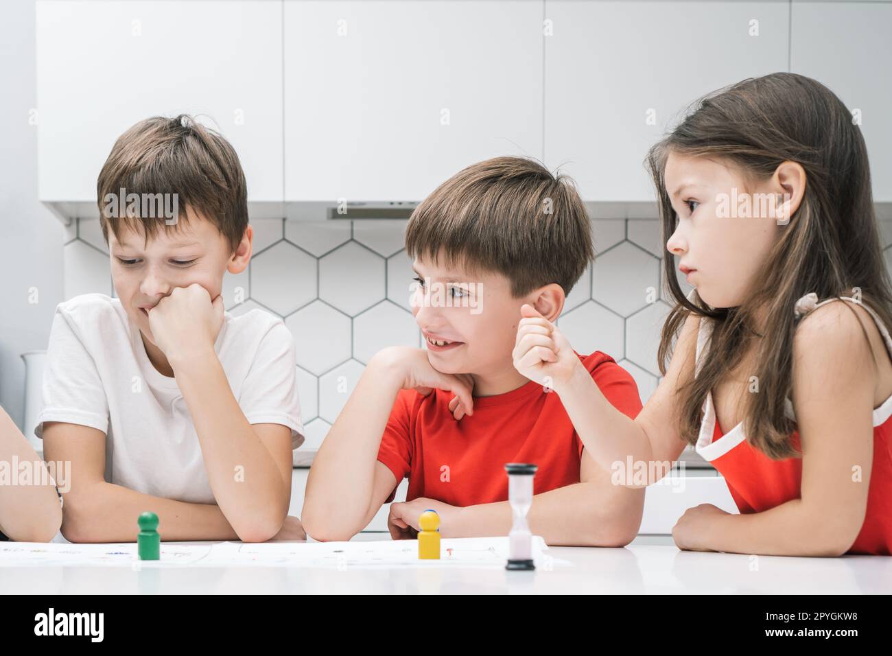 Joyful thoughtful kids, boys and girl playing board game with dice and time limit, listen to