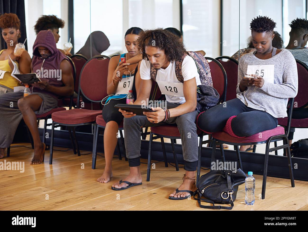This is taking forever...a group of young dancers sitting and waiting for their dancing auditions. Stock Photo