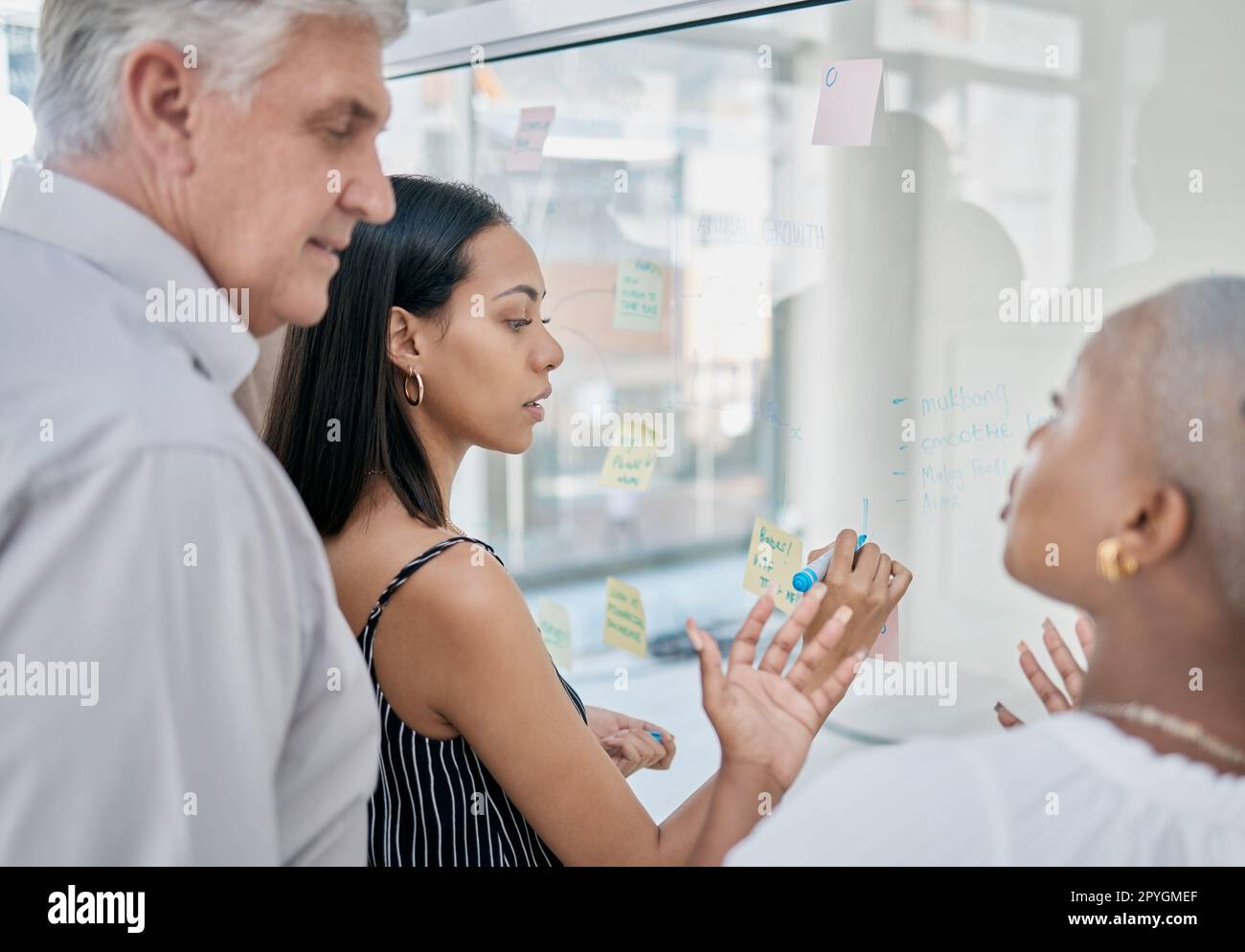 Innovation, meeting or woman writing on a sticky note planning a startup project on glass board in office building. Focus, leadership or creative business people working on strategy ideas or solution Stock Photo