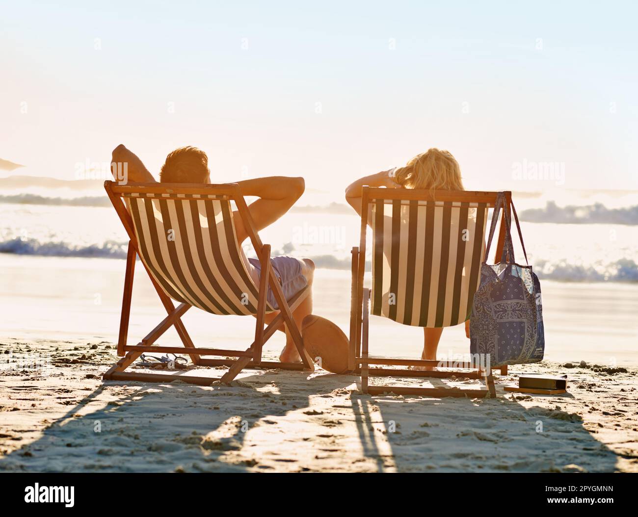 Lifes a beach. a couple admiring the sunset while seated on beach ...