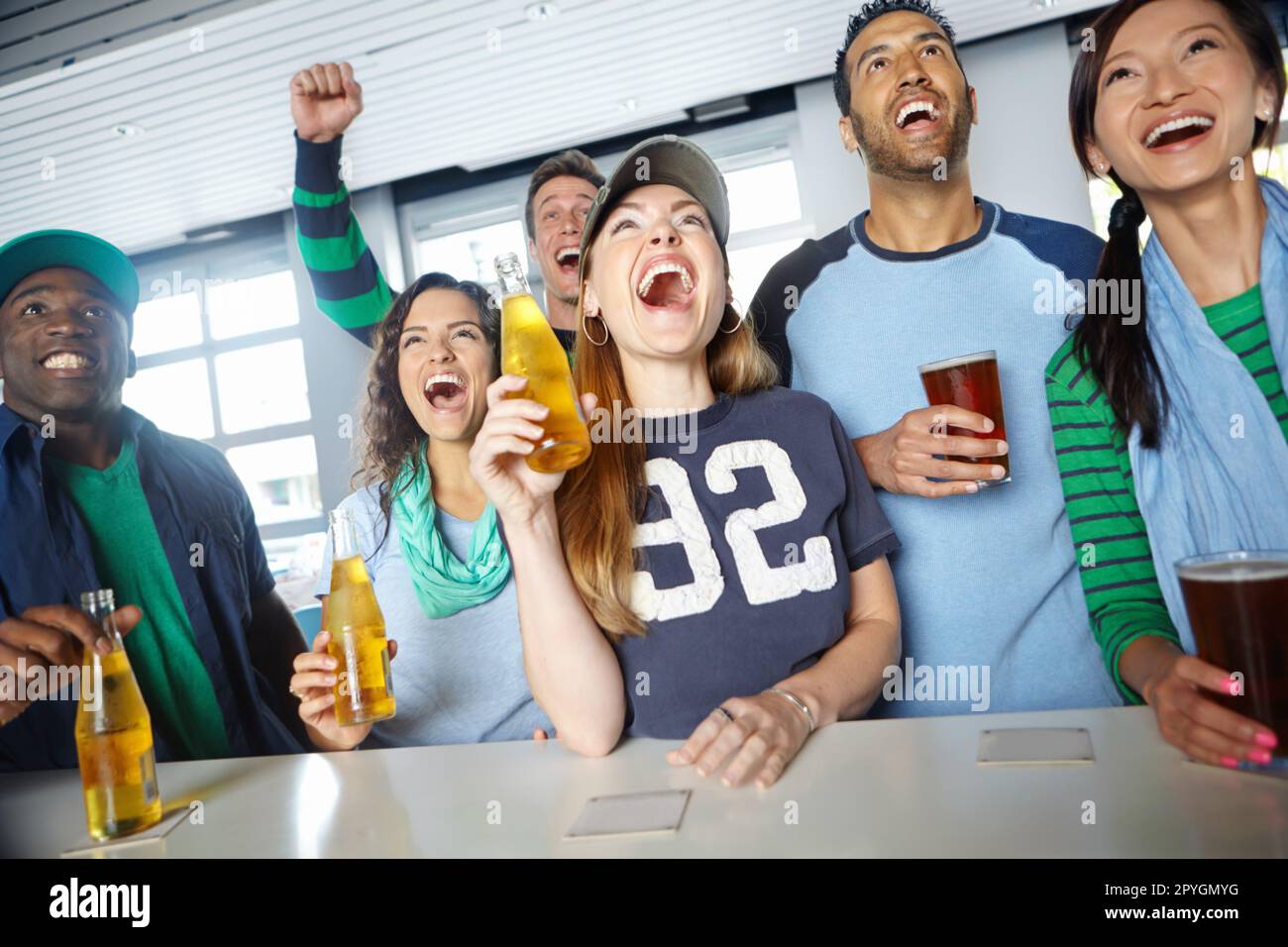 Drinks and sport with friends. A group of friends cheering on their favourite team at the bar. Stock Photo