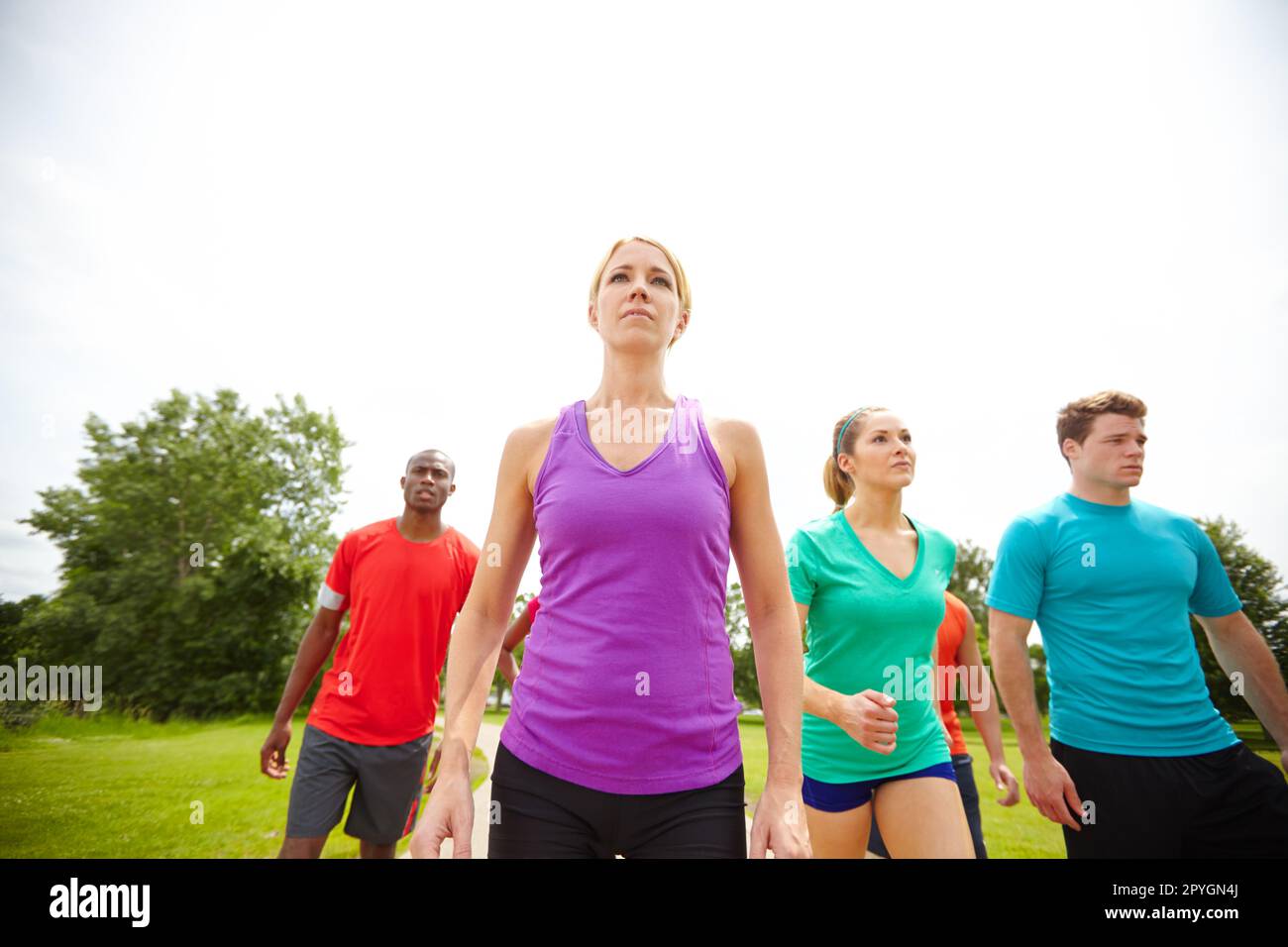Take a breath. Low angle shot of a group of athletes exercising outdoors. Stock Photo
