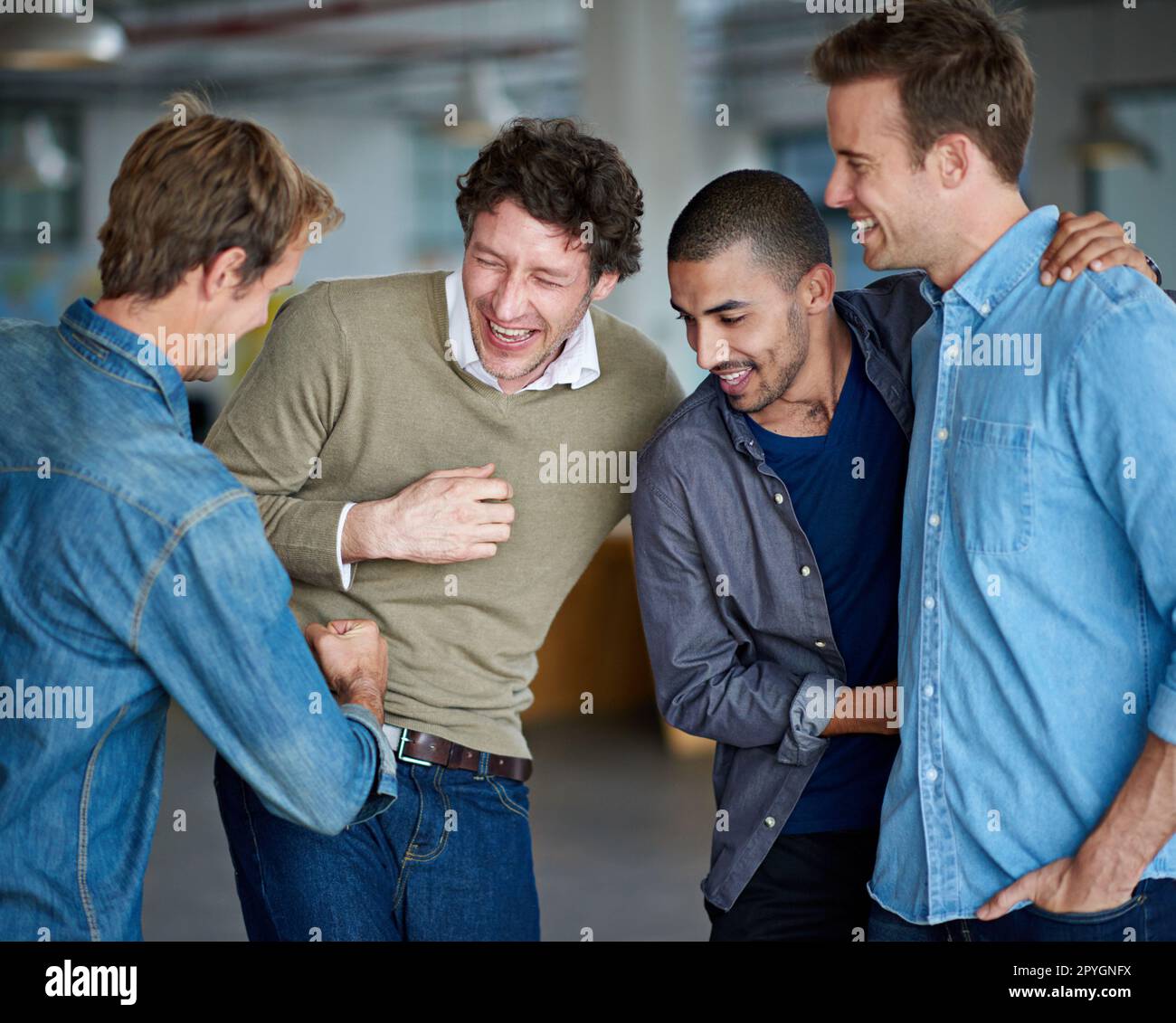 Time to test the macho. Group of male coworkers messing about and having a laugh. Stock Photo