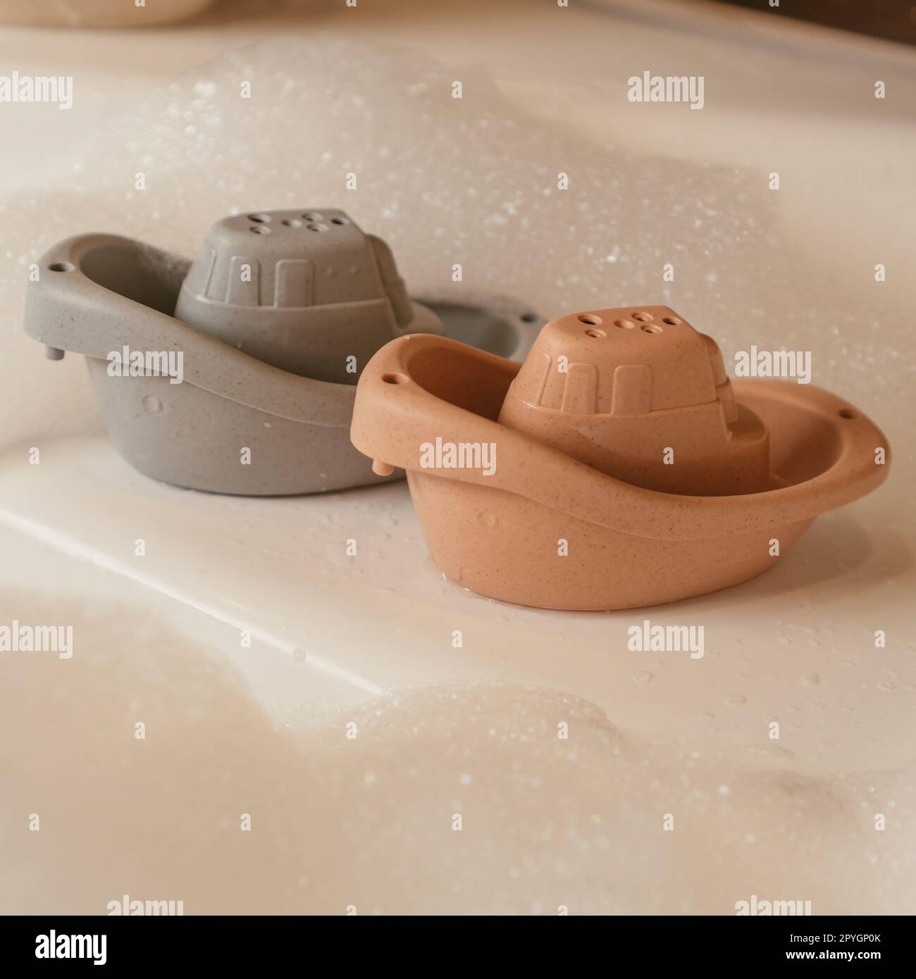Cute grey and orange small silicone toy boats putting on edge of white