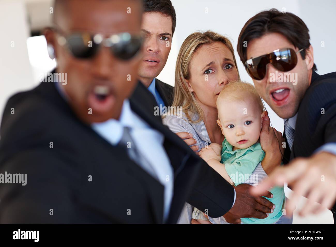 Responding to a threat. two bodyguards protecting their clients against a threat. Stock Photo