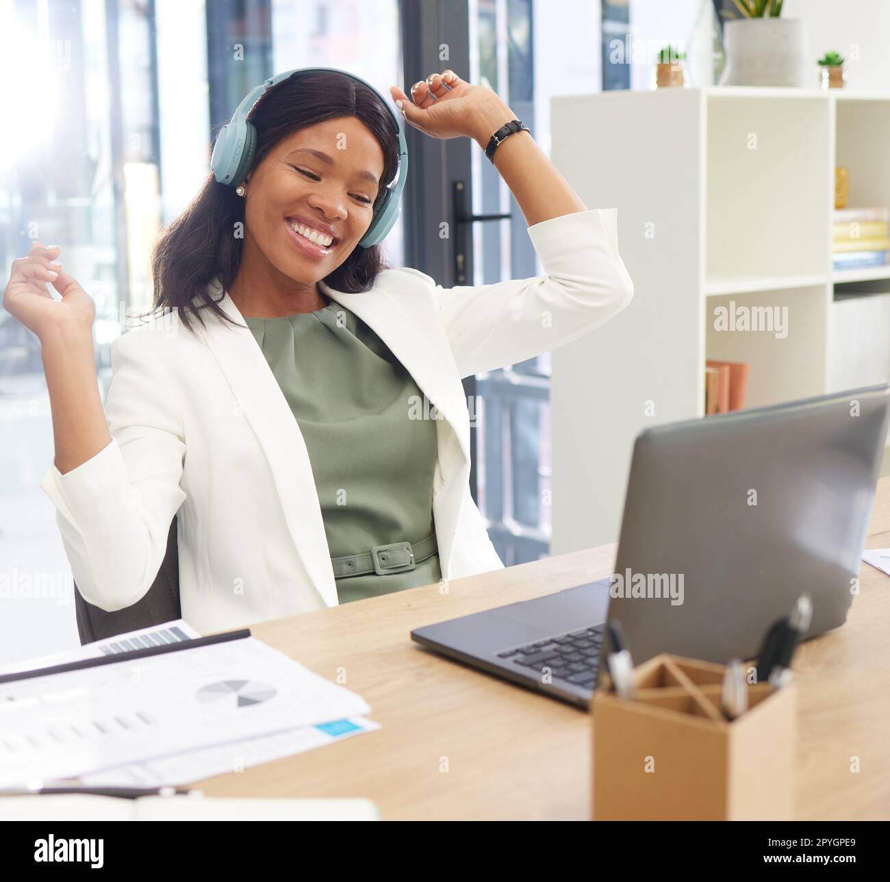 Business, black woman and celebration with headphones, excited and happiness in office. Female entrepreneur, manager or consultant with laptop, corporate deal and target for digital marketing or goal Stock Photo