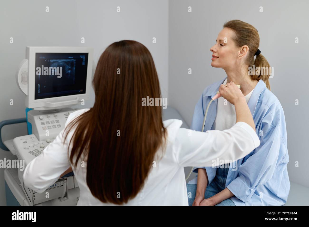 Woman doctor conducting ultrasound of thyroid gland and lymph nodes