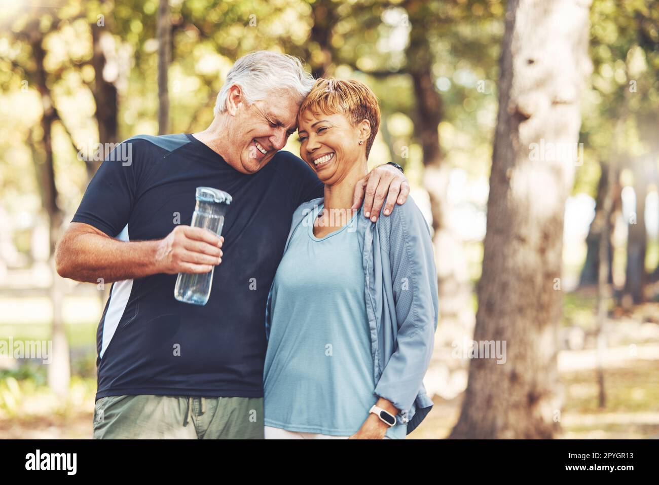 Fitness, funny or old couple of friends in nature laughing at a joke after training, walking or workout. Comic, support or happy senior woman bonding with elderly partner in interracial marriage Stock Photo