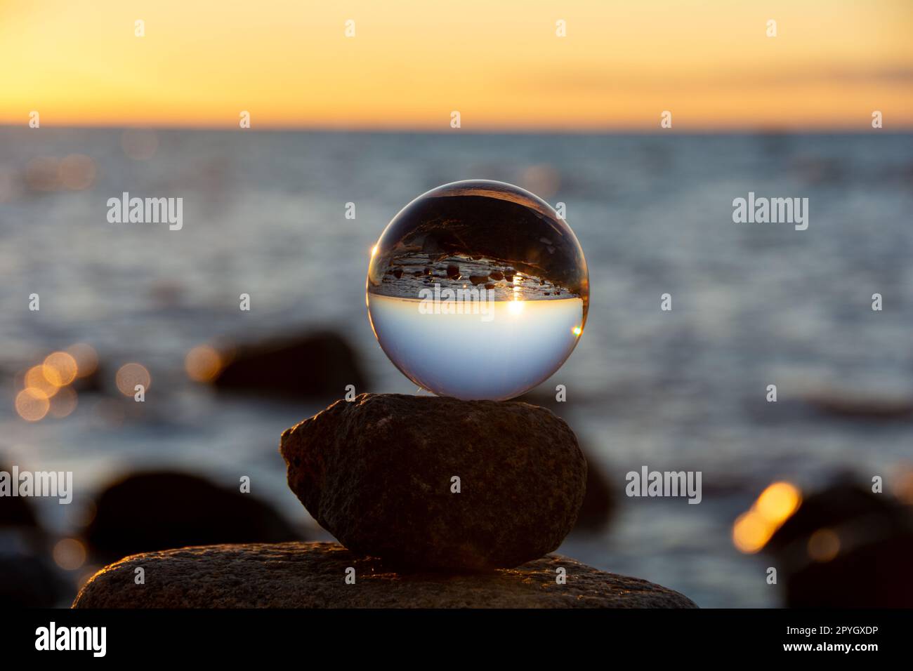 The glass ball lies on the top stone reflecting the beach and the sea ...
