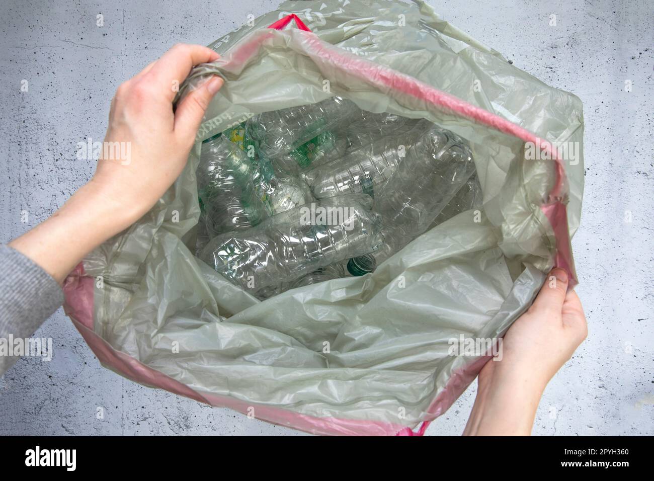 Hand getting plastic bottles to dispose in garbage bag ready to recycle, waste management and plastic recycle. Sorting waste plastic bottles top view Stock Photo