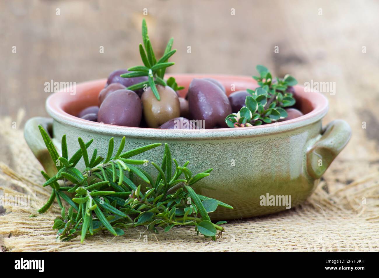 red kalamata olives and herbs in a bowl on wooden background Stock Photo