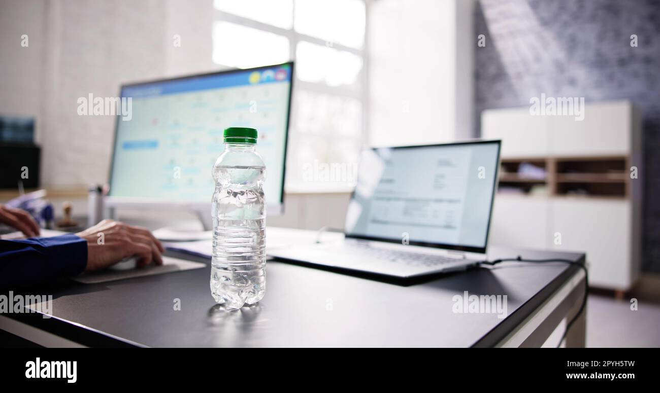 Water Bottle On Desk And Man In Background Stock Photo