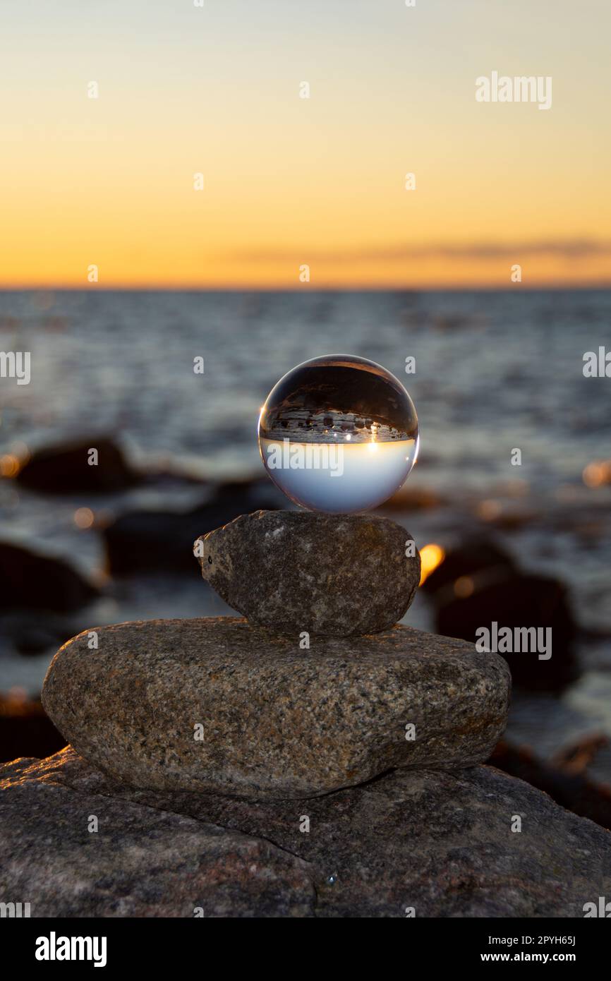 The glass ball lies on the top stone reflecting the beach and the sea ...