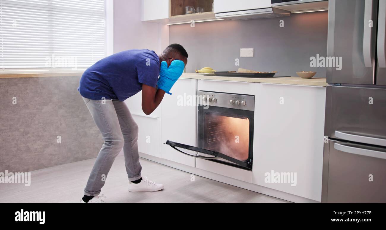 Shocked Young Man Looking At Smoke Coming Out Of Oven Stock Photo Alamy