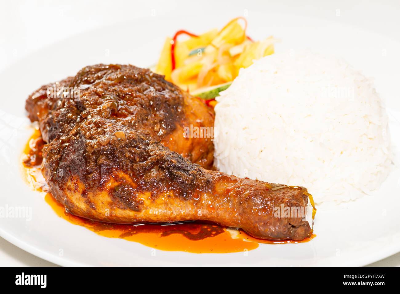 Chicken Rendang served with coconut milk rice and pickled vegetables Stock Photo