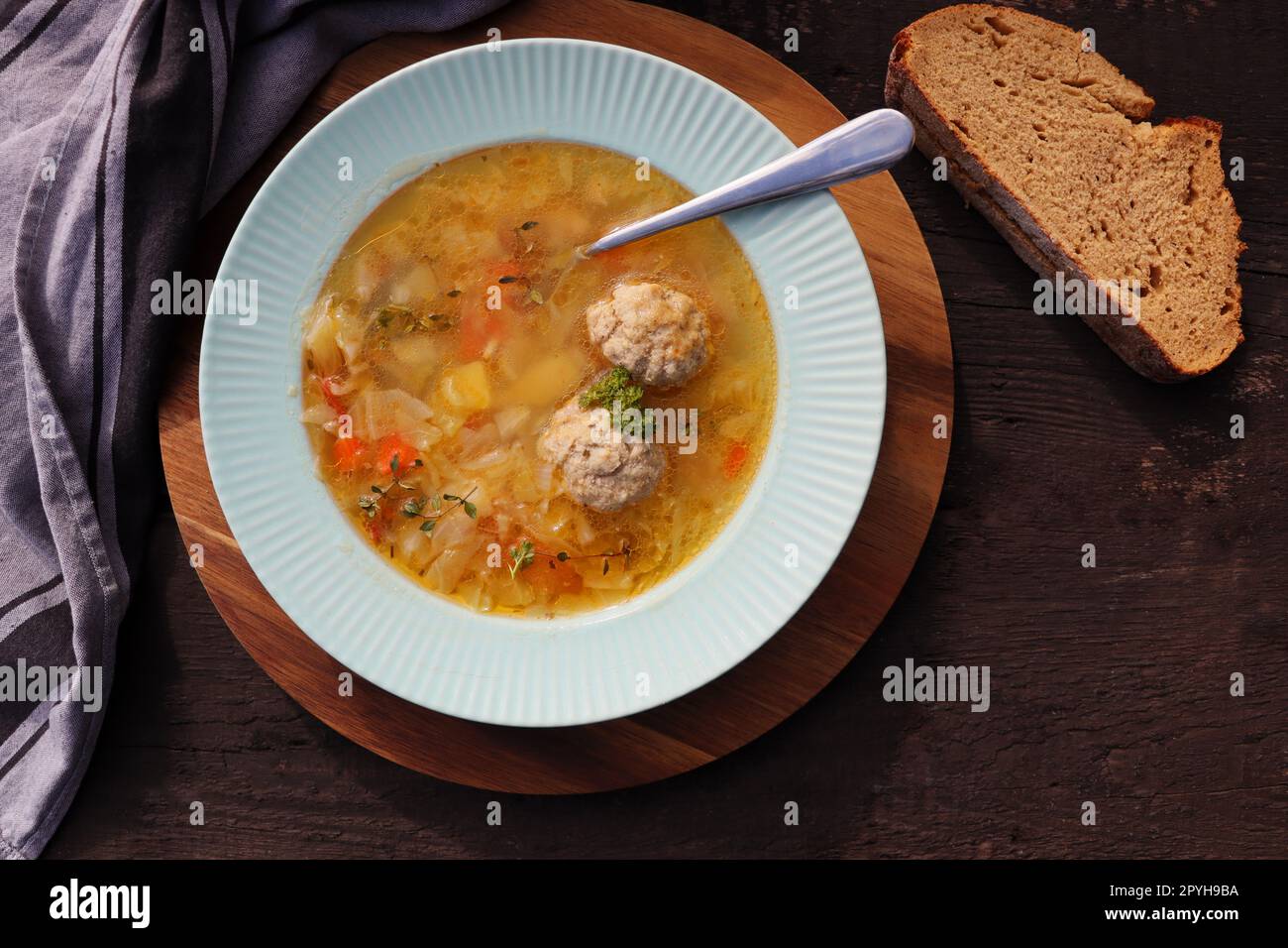 Soup with meatballs on dark background, gray linen napkin. Healthy meatball soup with vegetables. Top view Stock Photo