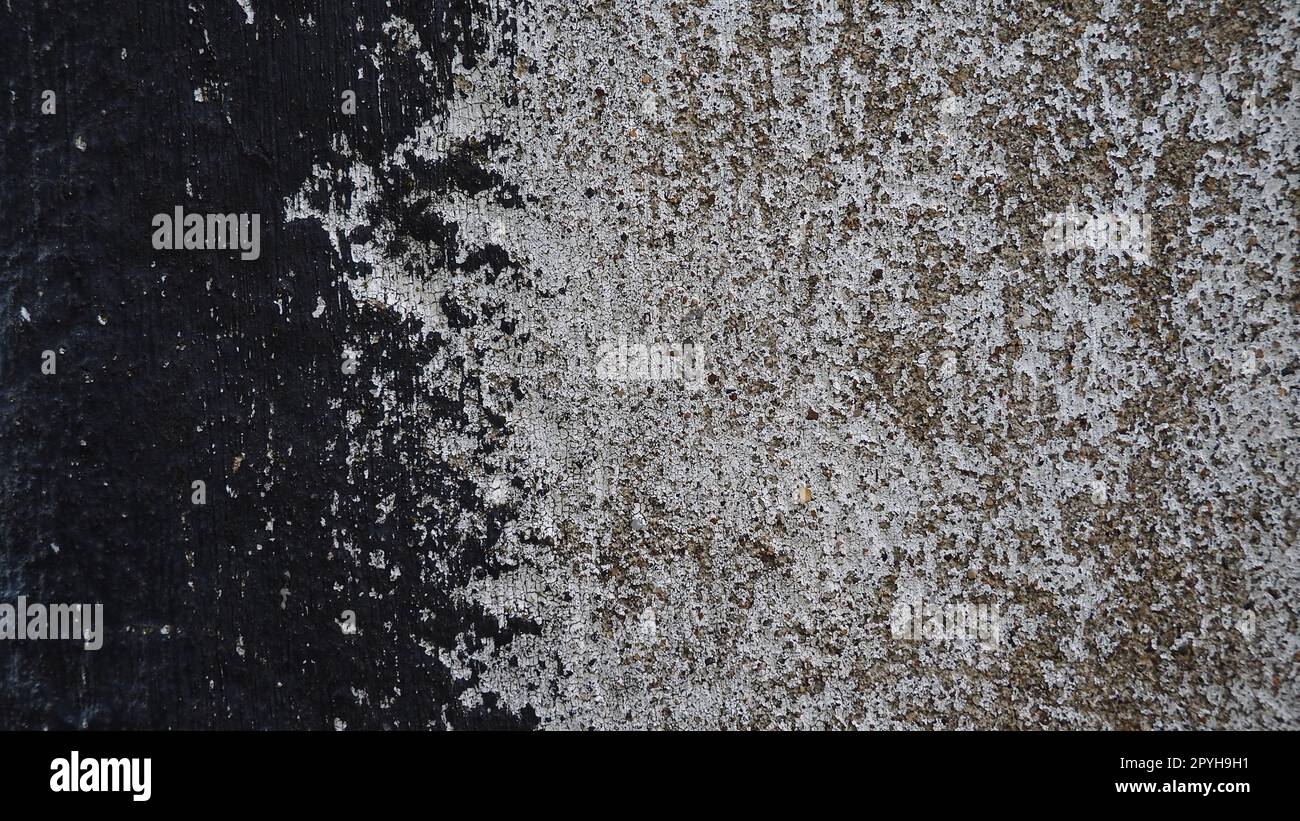 Concrete wall with black and white stripe of paint. Carelessly brushed parts, translucent gray plaster through the applied oil paint. Grunge background with empty space. Copy space Stock Photo