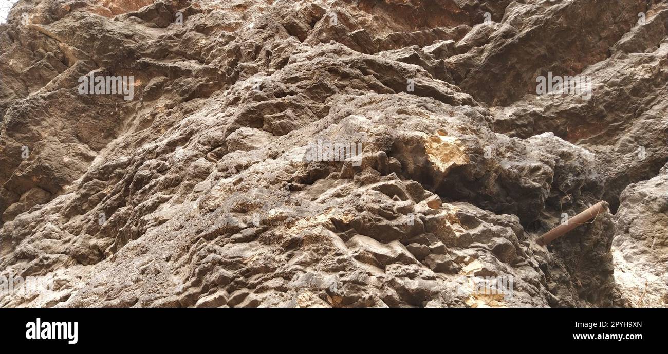 stone rock closeup. Sarajevo, Bosnia and Herzegovina. Ancient frozen lava. Layers and strata of rocks. Mountain after a guided explosion to lay the road. Texture of the stone. Gray and beige colors. Stock Photo