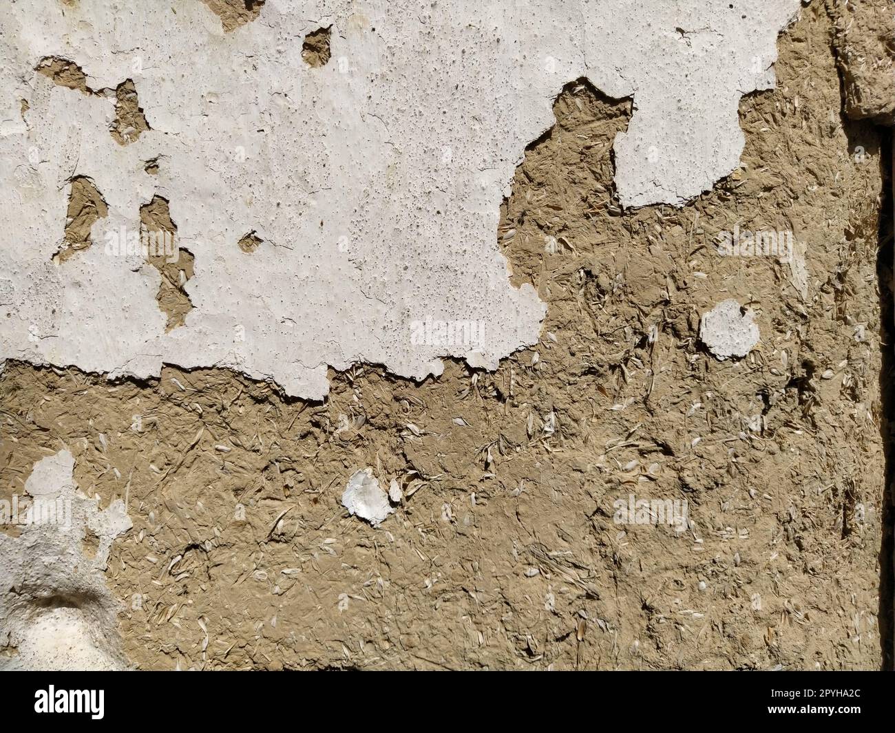 Close-up background of the wall of an old house made of clay mixed with straw. Old type of construction. Clay wall of straw and mud. Manure mixed with clay and dried as building material Stock Photo