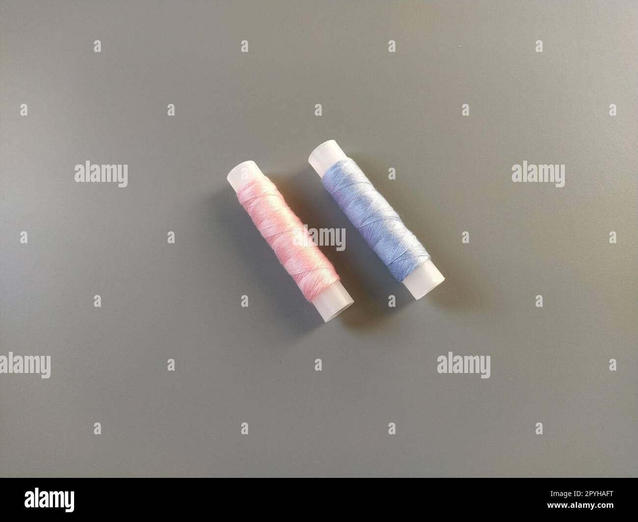 Spools of pink and blue thread on a gray background. Textile industry Stock Photo