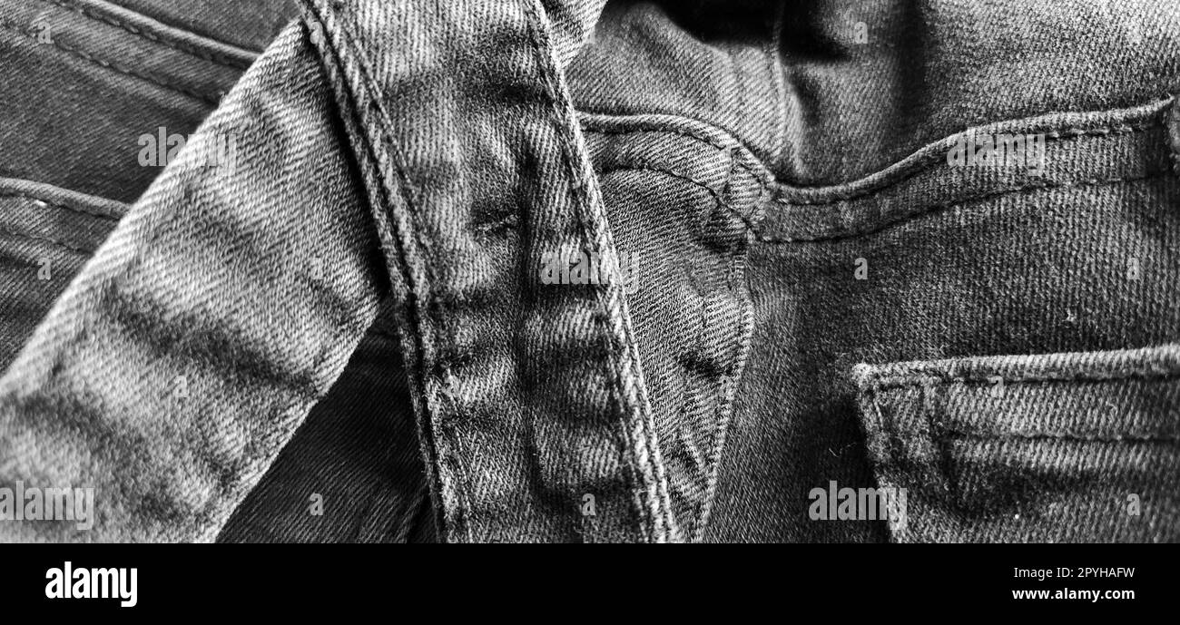 Fashionable denim clothing. Details and seams on rough denim. Black and