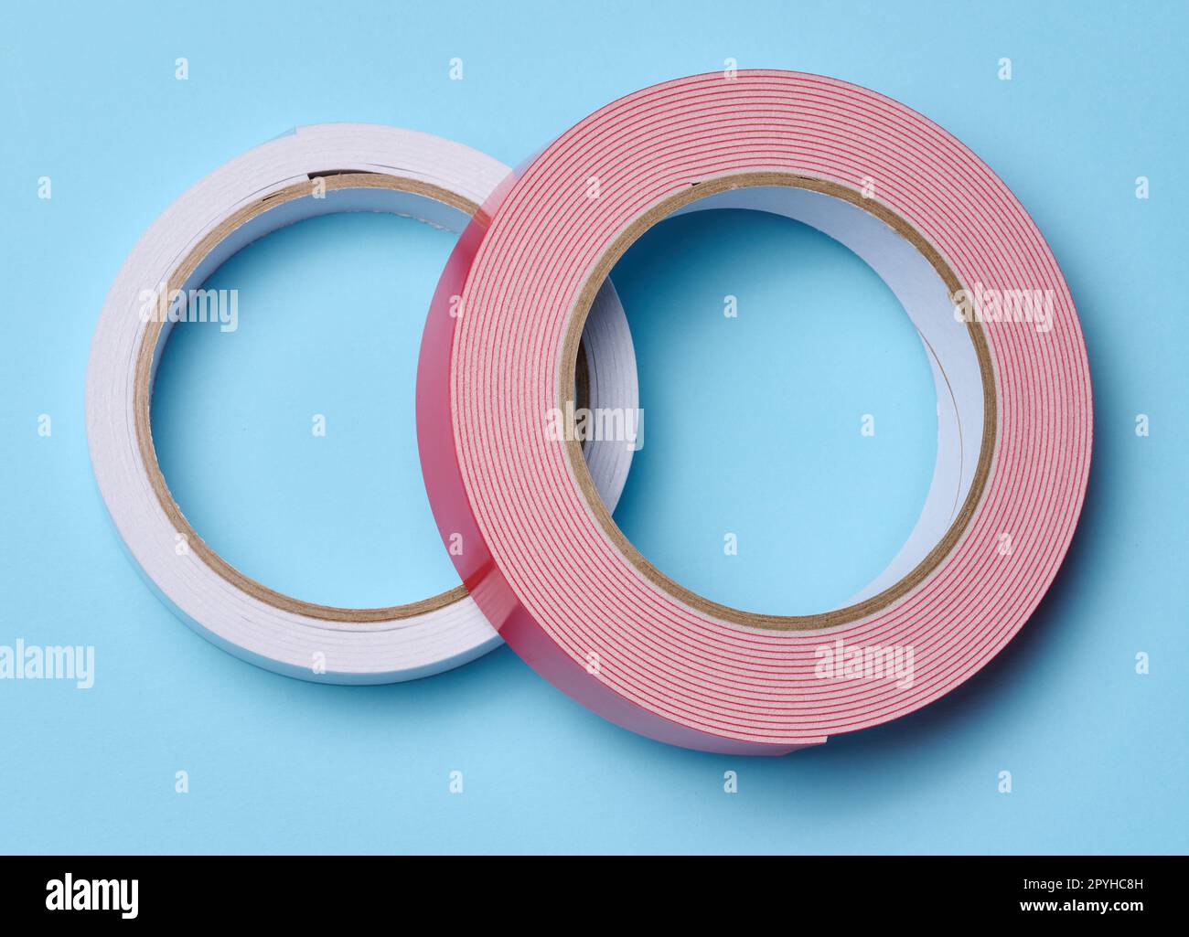 Two rolls of double-sided sticky tape on a blue background, top view Stock Photo