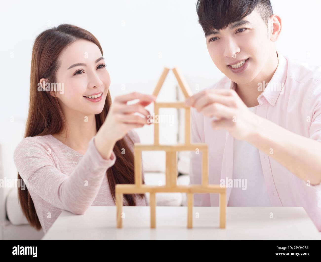 Happy young couple building house by with wooden bricks for home ...