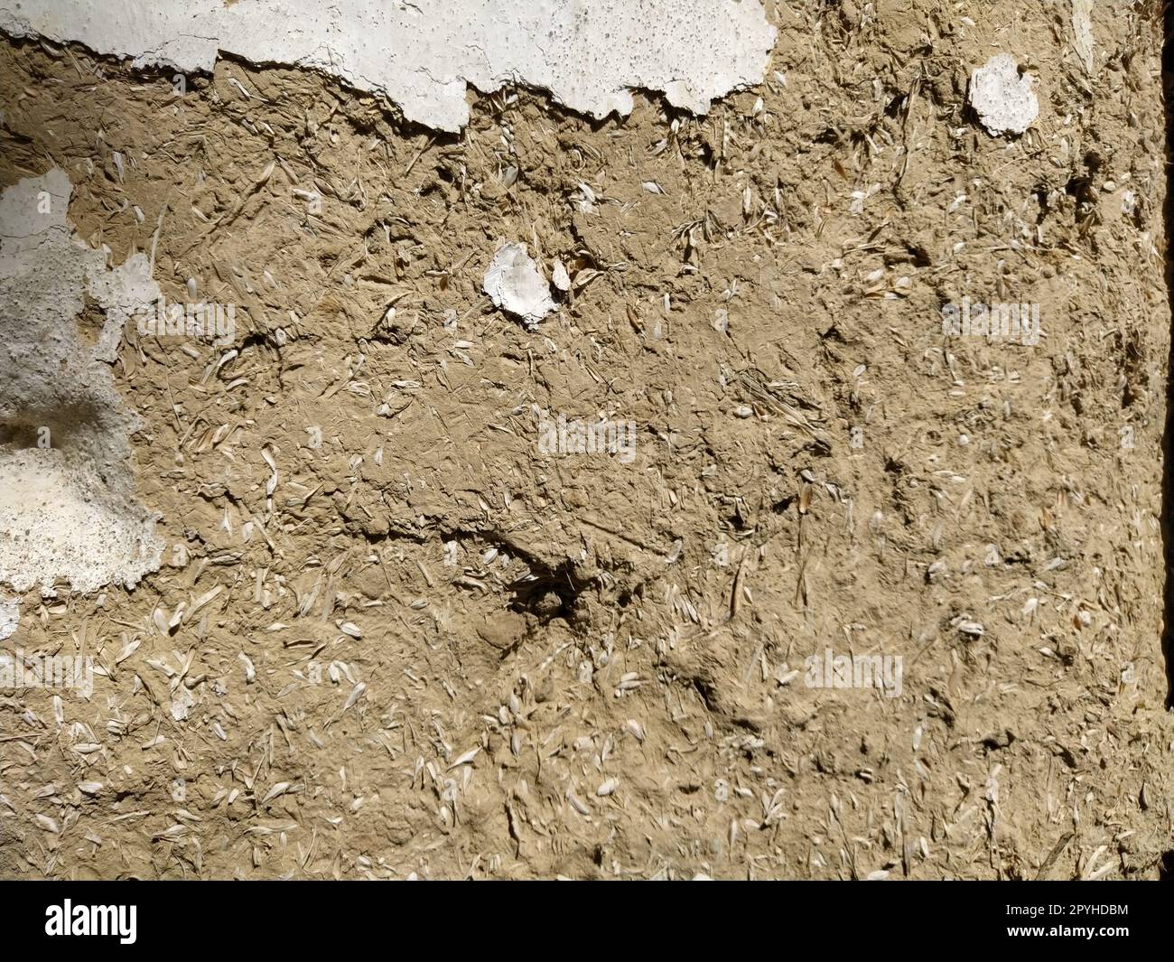 Close-up background of the wall of an old house made of clay mixed with straw. Old type of construction. Clay wall of straw and mud. Manure mixed with clay and dried as building material Stock Photo