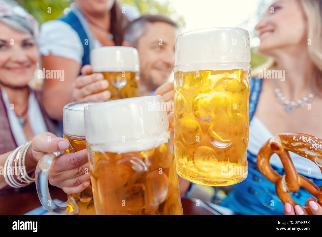 Clinking with beers in Bavarian beergarden Stock Photo