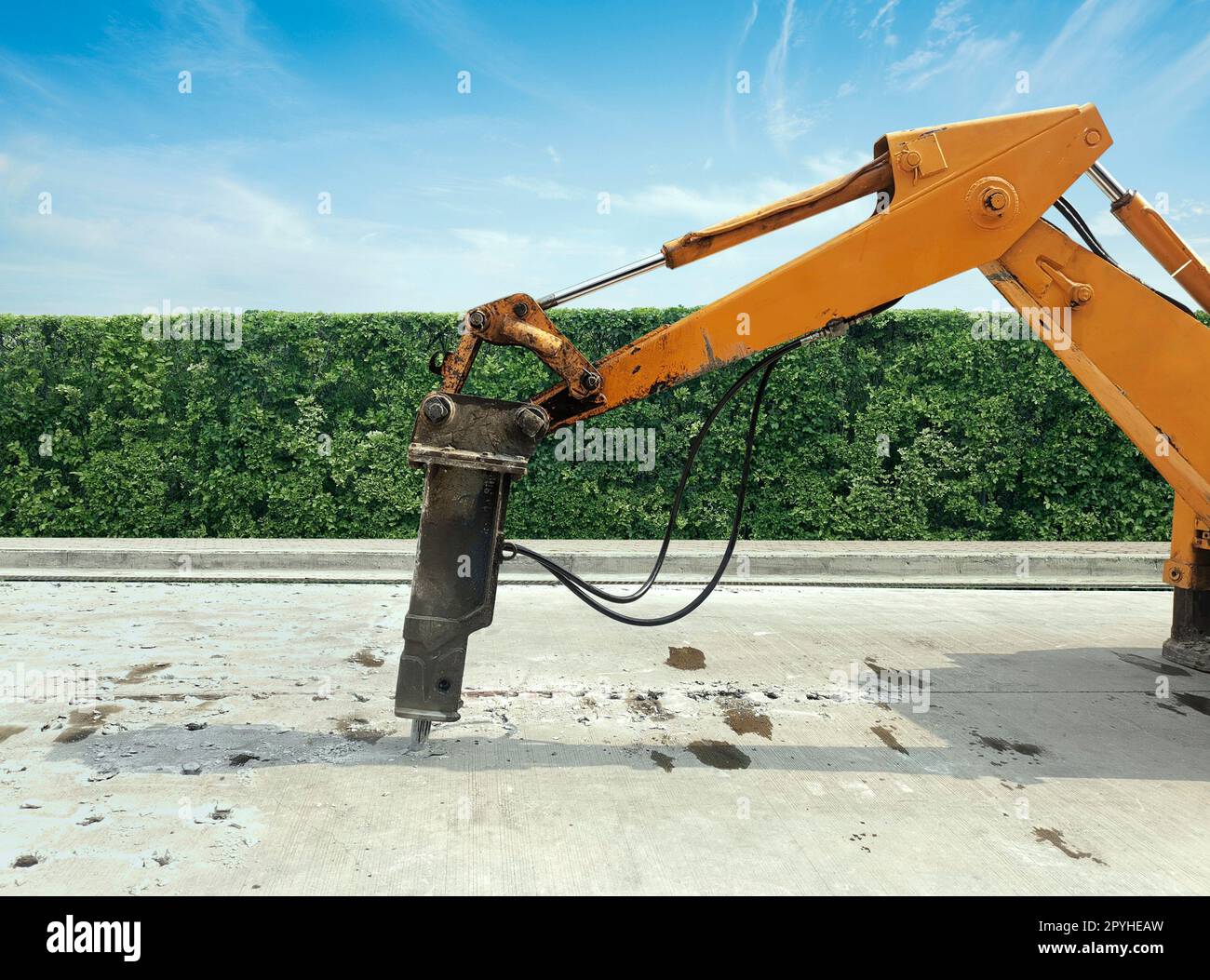 Excavator breaking and drilling the concrete road for repairing. Large pneumatic hammer mounted on the hydraulic arm of a construction equipment.Construction Vehicles repairing road.drilled jackhammer Stock Photo