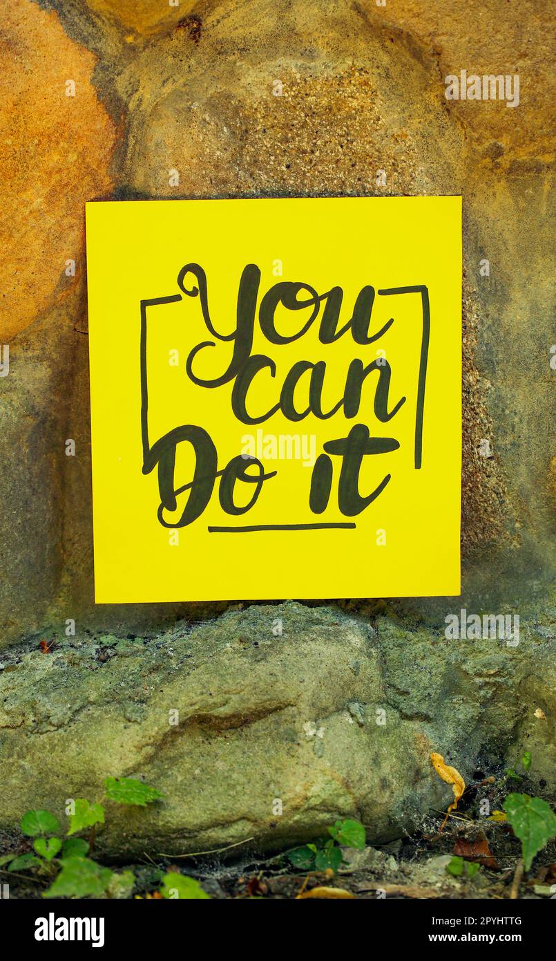 Yellow paper note with phrase You Can Do It on stone background Stock Photo