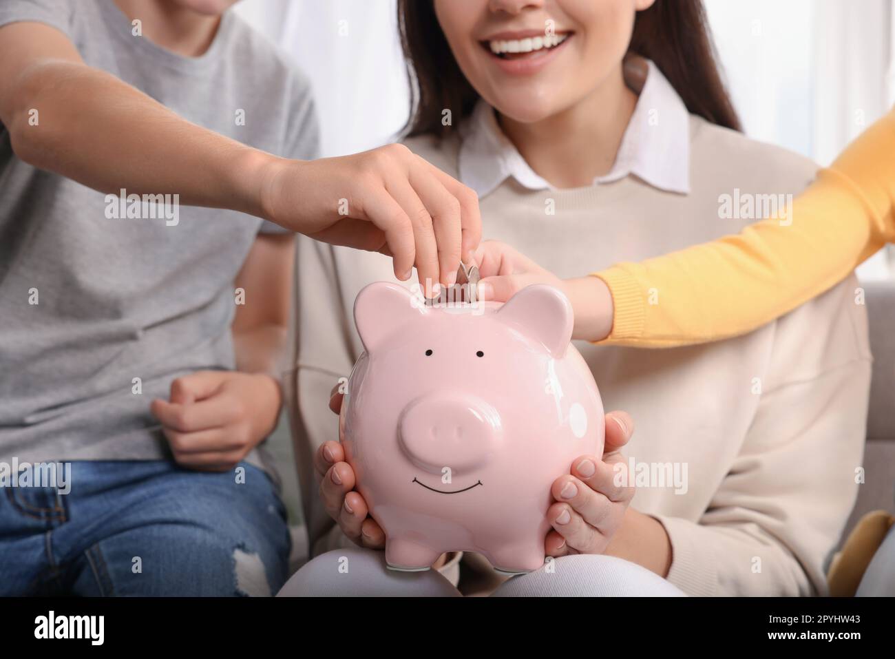 Happy family putting coins into piggy bank at home, closeup Stock Photo ...