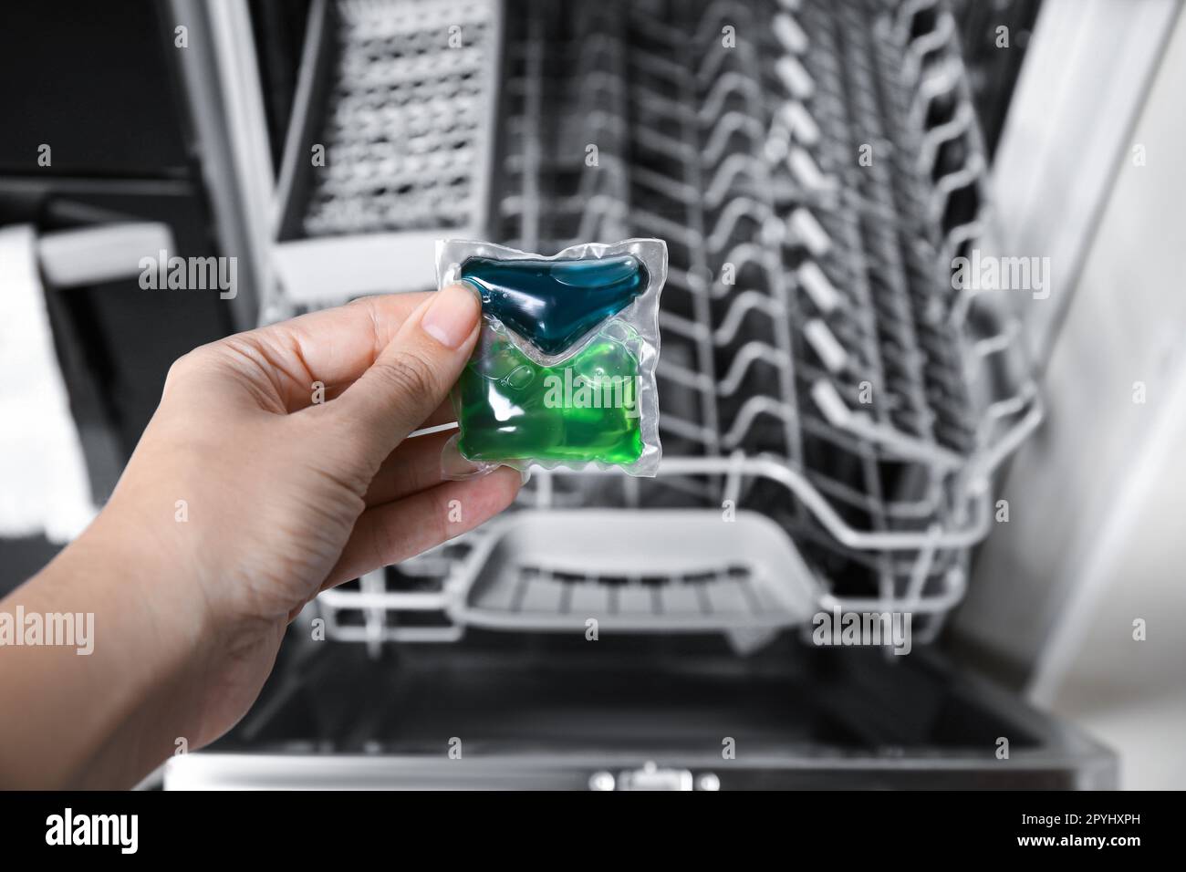 Woman putting detergent pod into open clean modern empty automatic