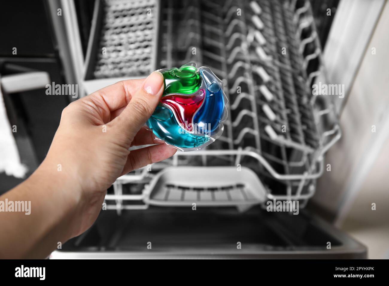 Woman putting detergent pod into open clean modern empty automatic
