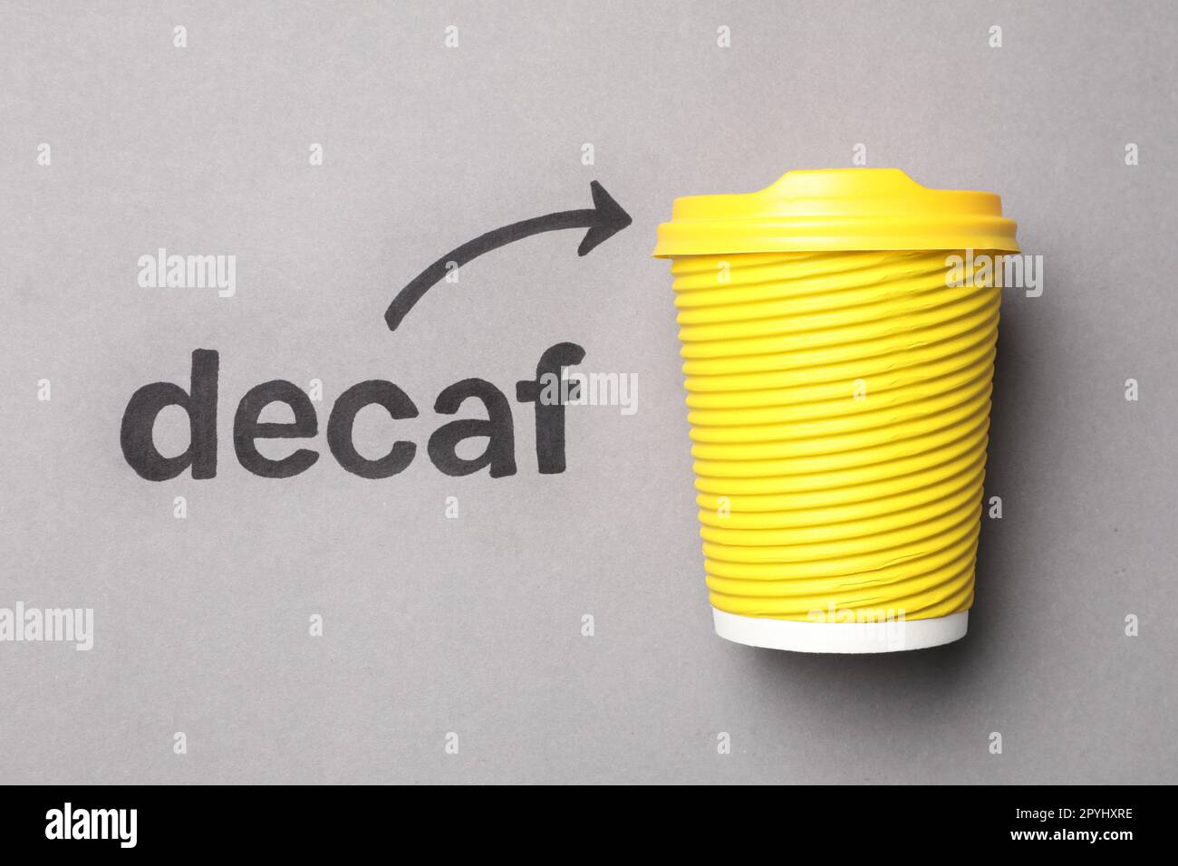 Word Decaf and arrow pointing at takeaway paper coffee cup on light ...