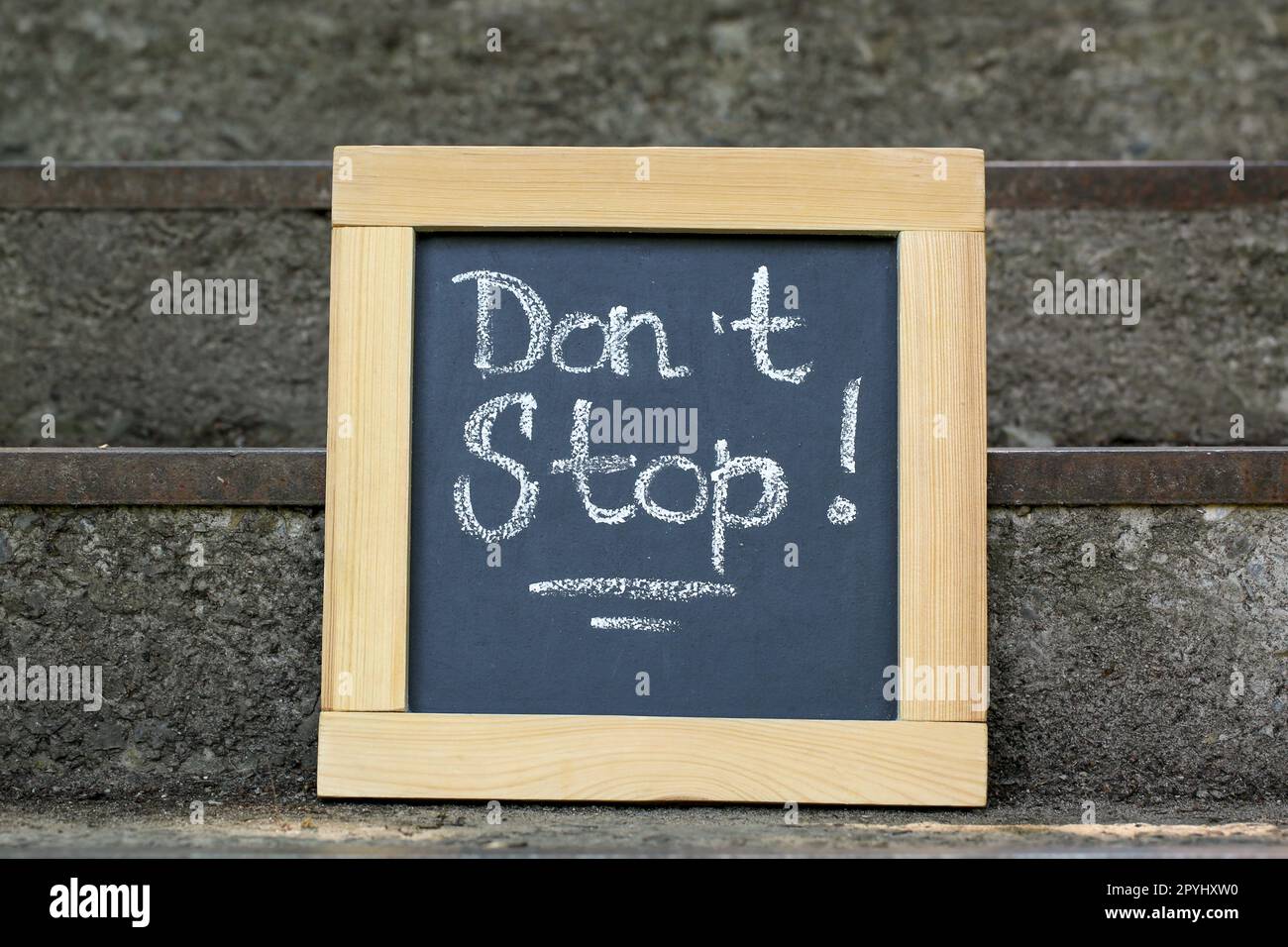 Chalkboard with phrase Don't Stop on stone stairs outdoors Stock Photo