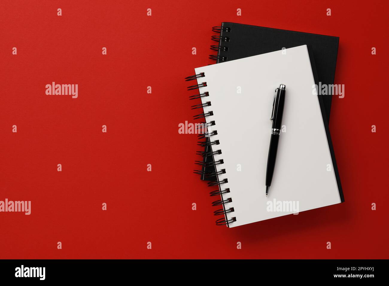 Notebooks and pen on red background, top view. Space for text Stock Photo