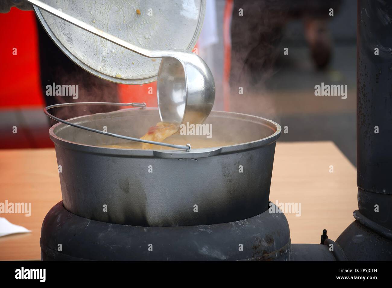 Outdoor preparing soup in a cast iron boiler, feeding homeless people