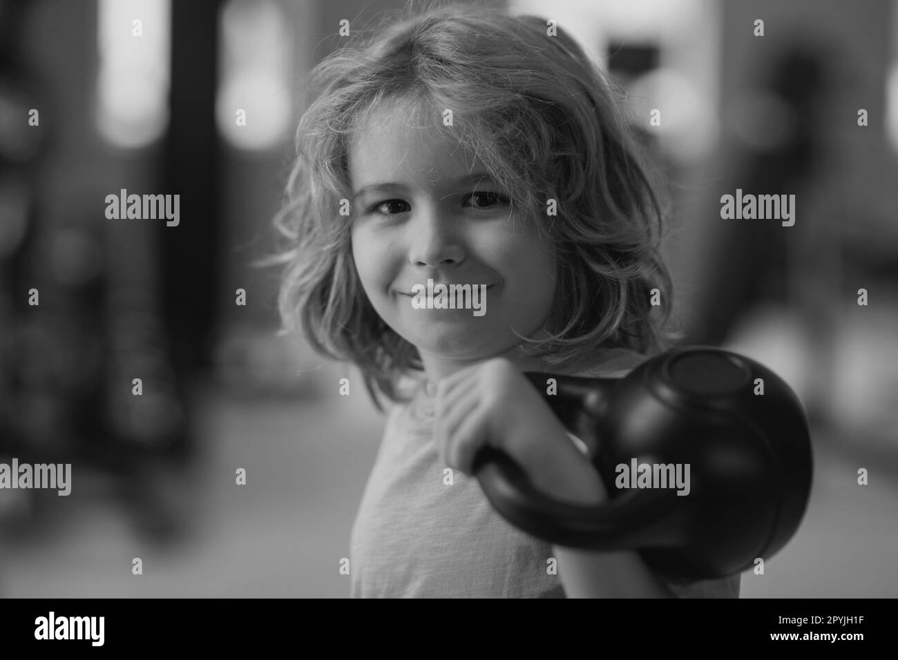Kid workout kid in gym. Kid raising a kettlebell. Cute child training