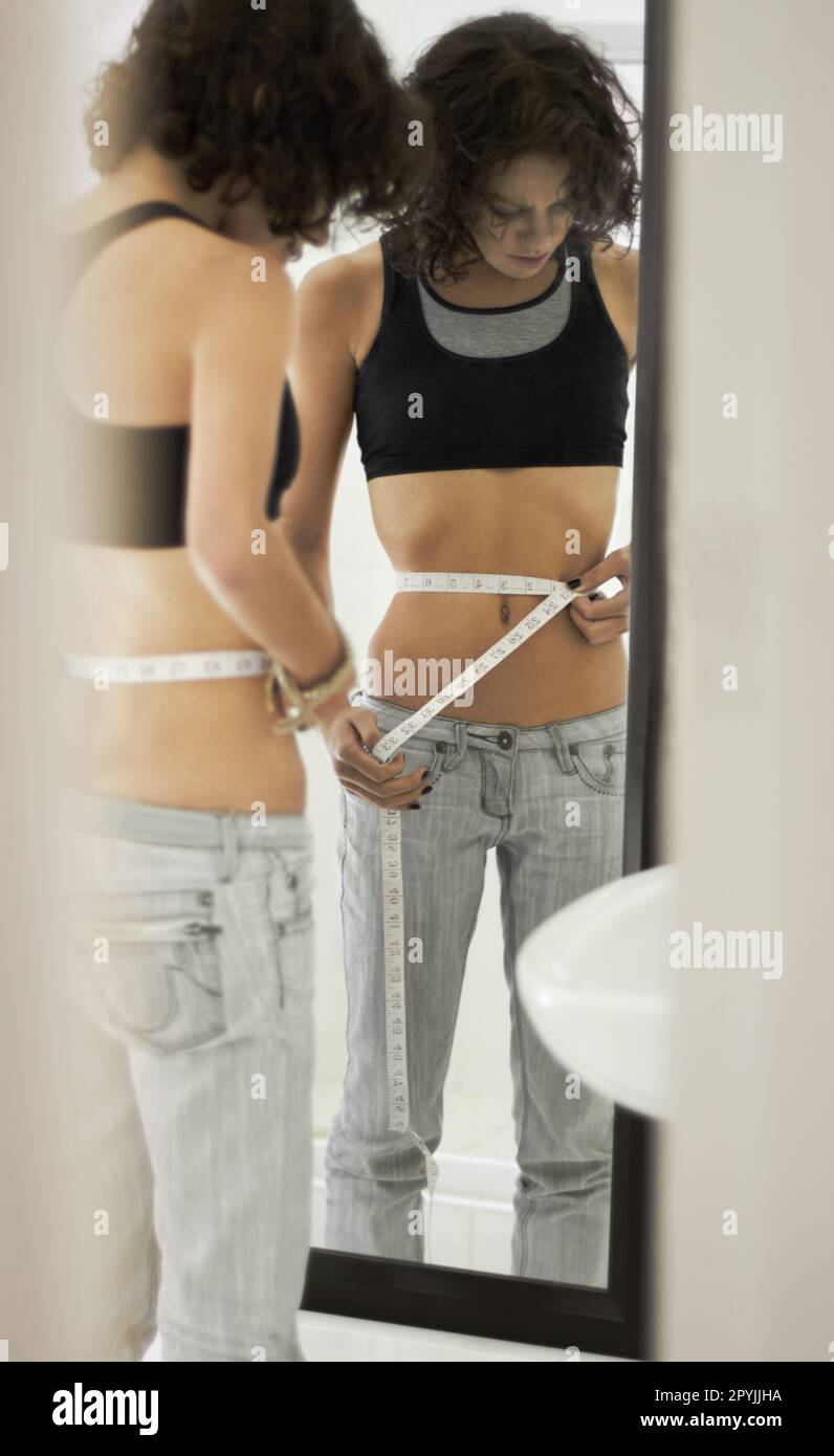 Anorexia, tape and sad woman in mirror for eating disorder, anxiety and mental health. Depression, weight loss and measuring with female and Stock Photo