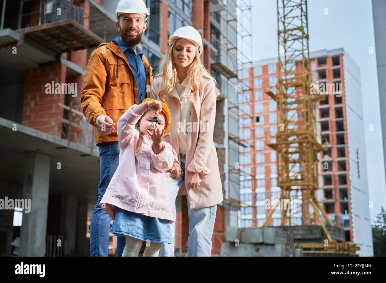 Contruction Project Parents Daughter holding apartment keys and smiling while standing next to ...
