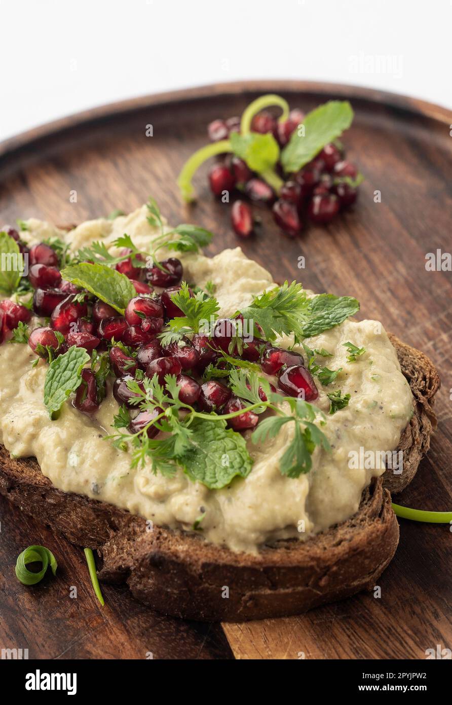 Baba ghanoush eggplant dip and pomegranate seeds on toast with wood